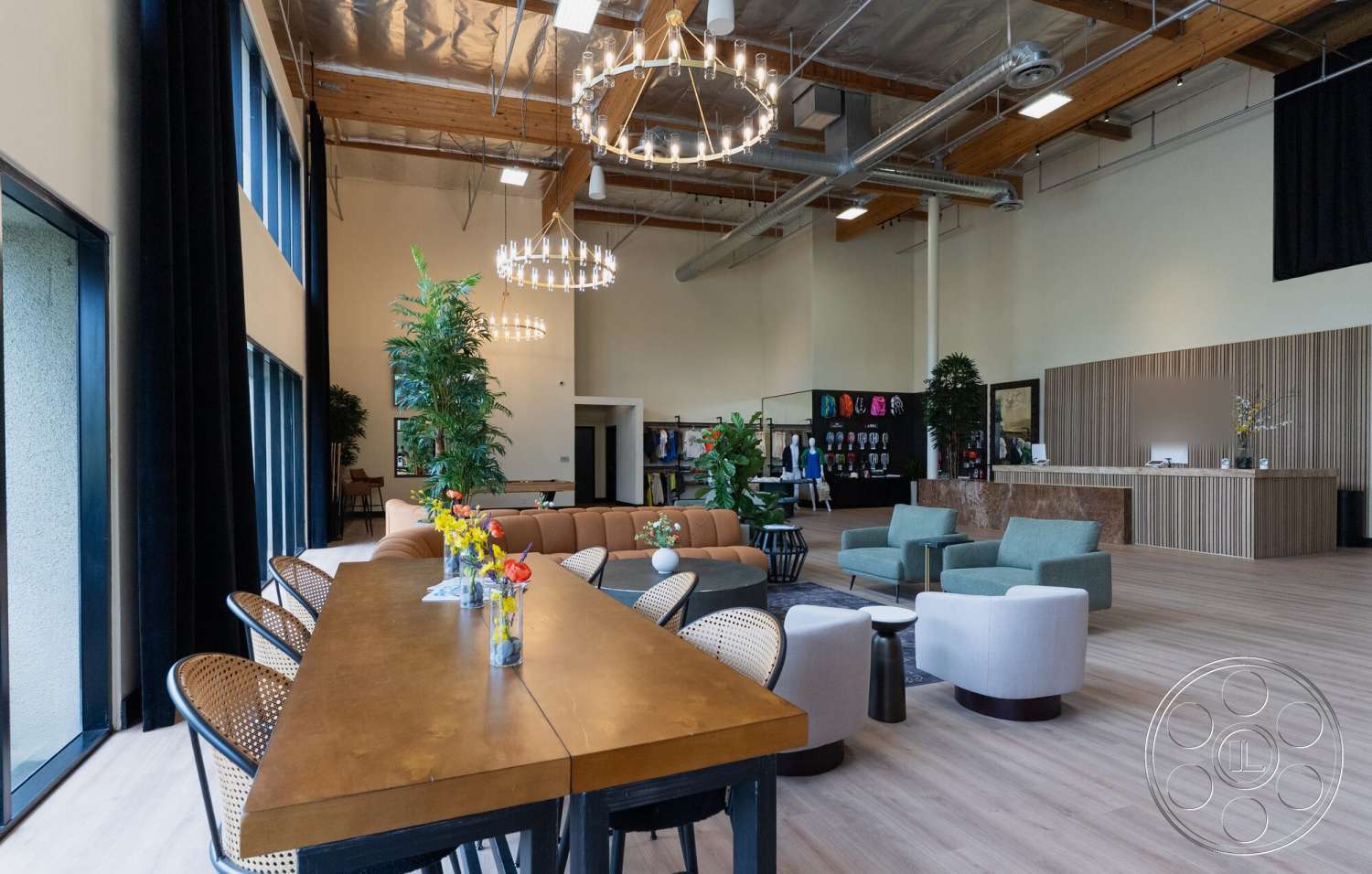 Gym 38 - neutral color palette, wood dining table, green indoor plants, open concept space, large floor-to-ceiling windows, contemporary seating area, exposed wood ceiling beams, modern chandelier lighting, industrial style architecture, wood panel reception desk, light wood laminate flooring, casual meeting space, woven rattan dining chairs, high ceiling commercial interior