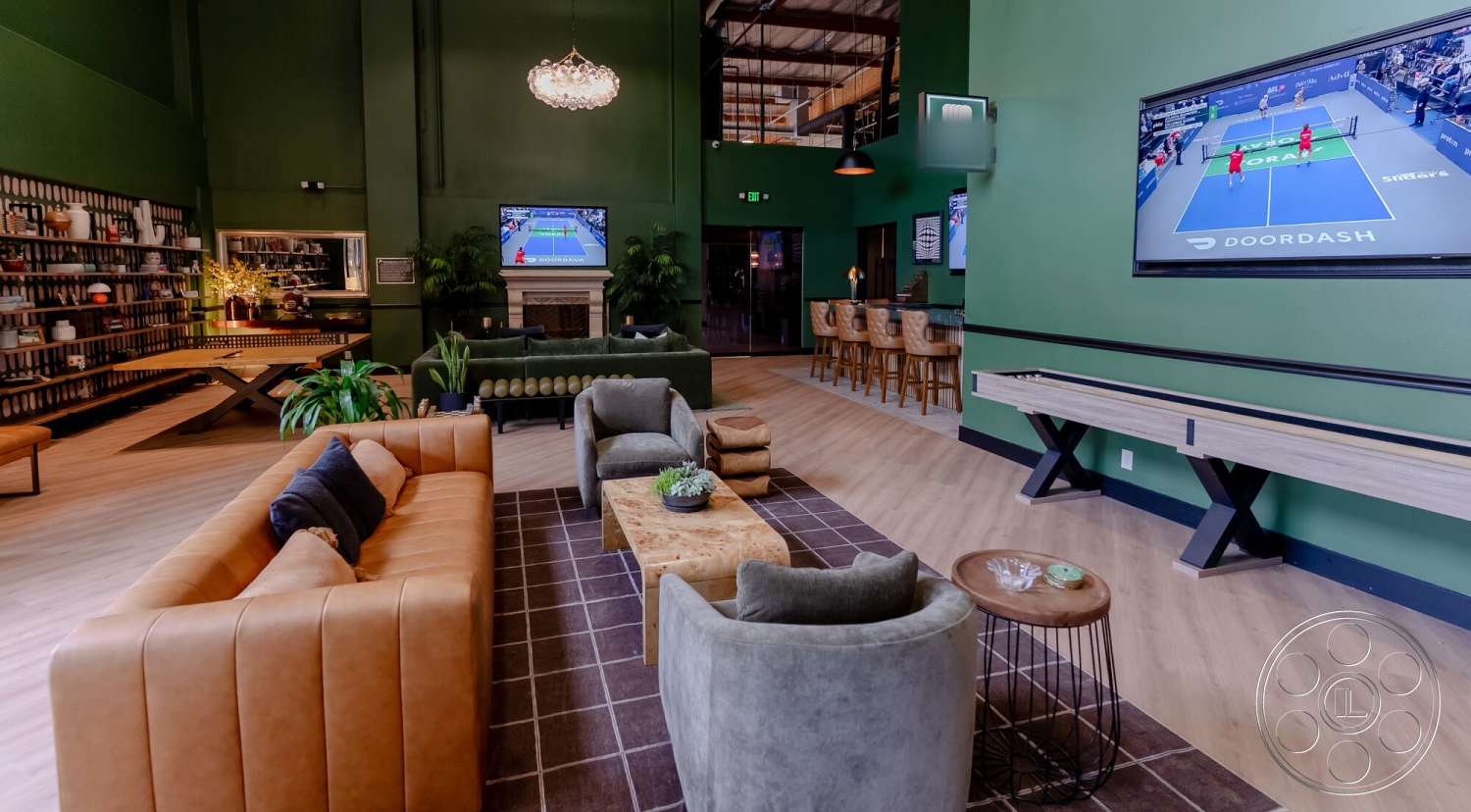 Gym 38 - recessed lighting, wood coffee table, bar seating area, large open space, modern style, wooden floor, potted greenery, flat-screen TV, contemporary chandelier, tan leather sofa, built-in shelving unit, green painted walls, black metal side table, dark gray upholstered armchair